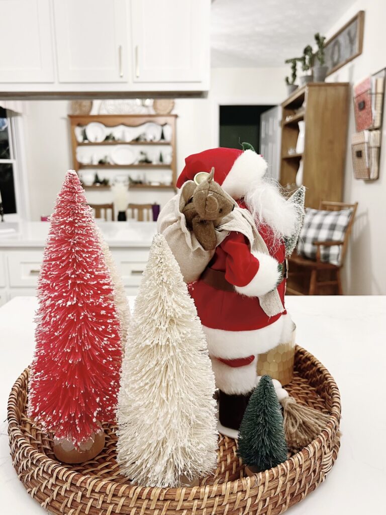 Side view of santa with bottle brush trees on a wicker tray for a centerpiece
