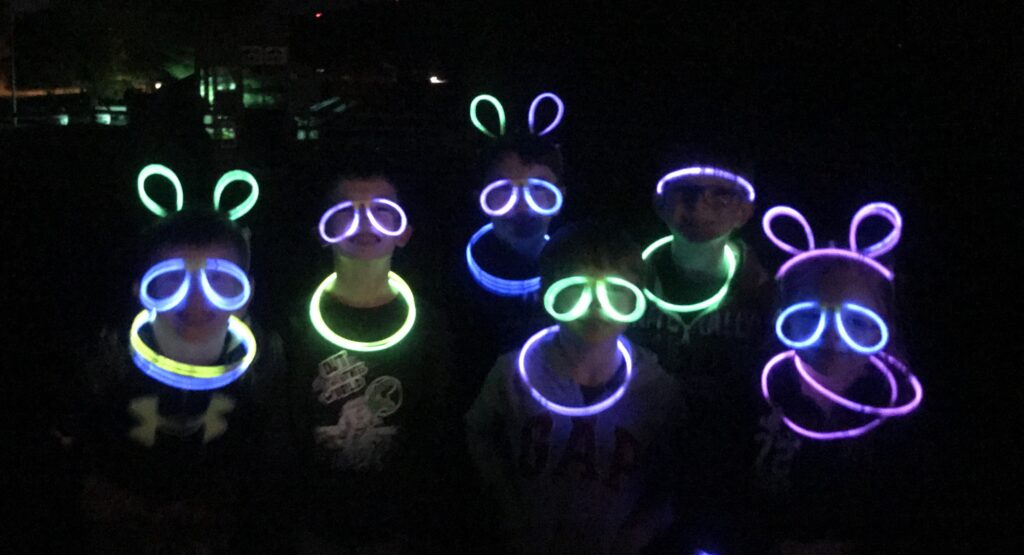 Kids with glow sticks on their faces and using them for Micky Mouse ears.