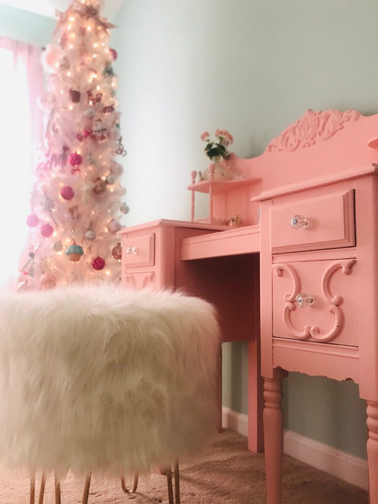 Here is a picture of the vanity in her room with her Christmas tree in the background and a white fur stool. 