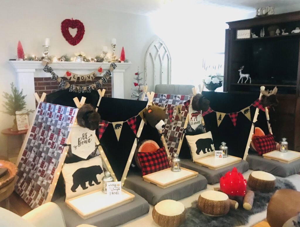 Tents set up for indoor party with faux camp fire and wild life accessories 