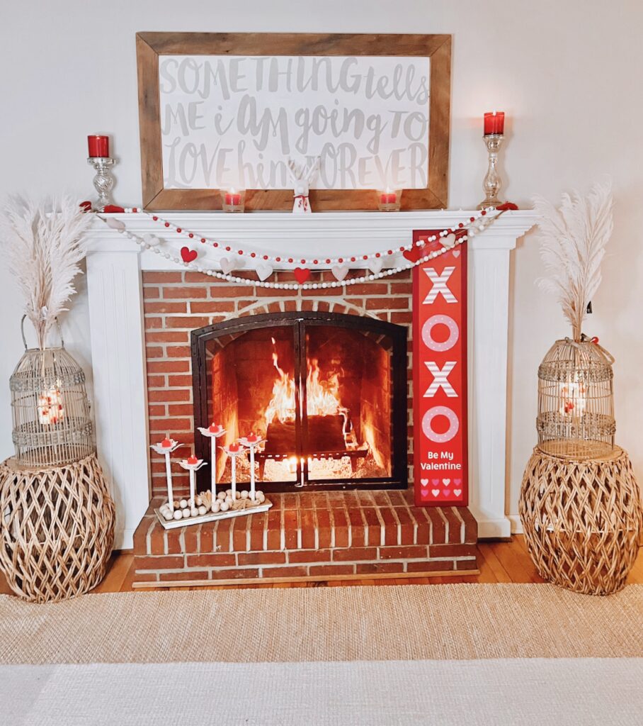 Fireplace with mantle and hearth decorated for Valentine's Day with heart garland, red candles, and XOXO sign.
