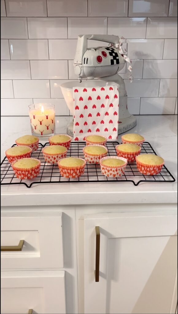 Cupcakes on a cooling rack in front of vintage mixer with tea towel